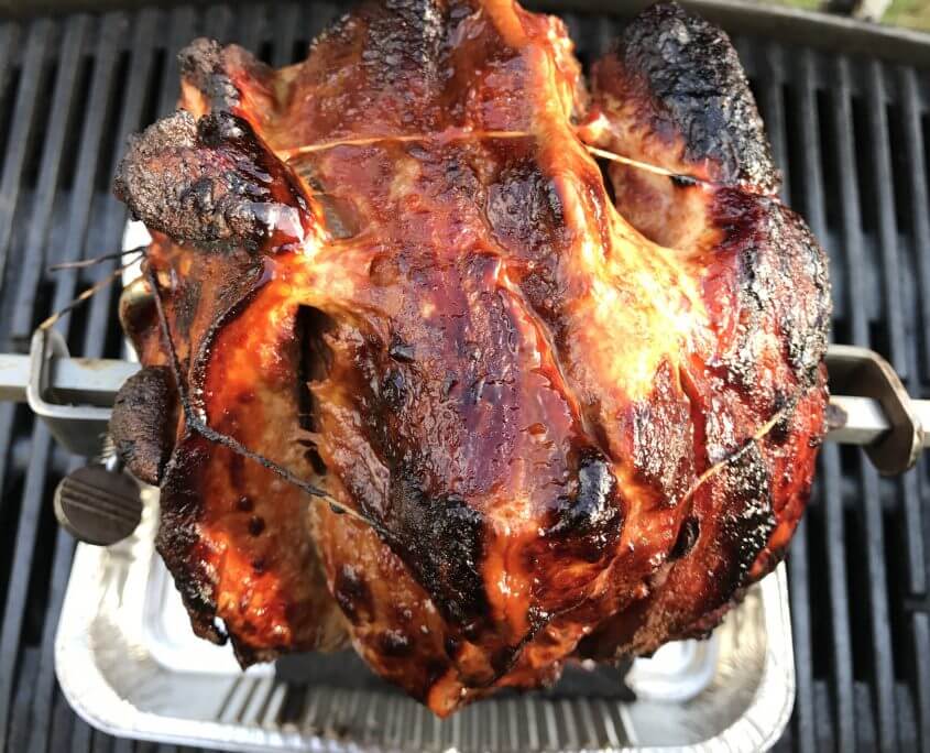 Krustenbraten vom Schweineschinken im Grill auf der Rotisserie